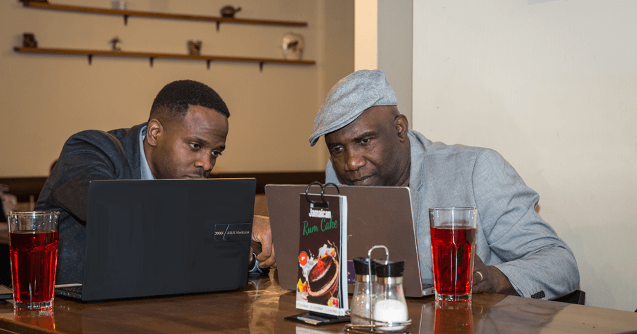Casual Business Meetings – Great Food, Fresh Drinks, and a Productive Atmosphere Two men having a business meeting over drinks, working on laptops in a relaxed setting
