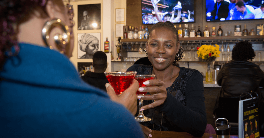 Lively bar vibes – cocktails, conversation, and sports action Casual night out – two women enjoying cocktails while fans watch sports